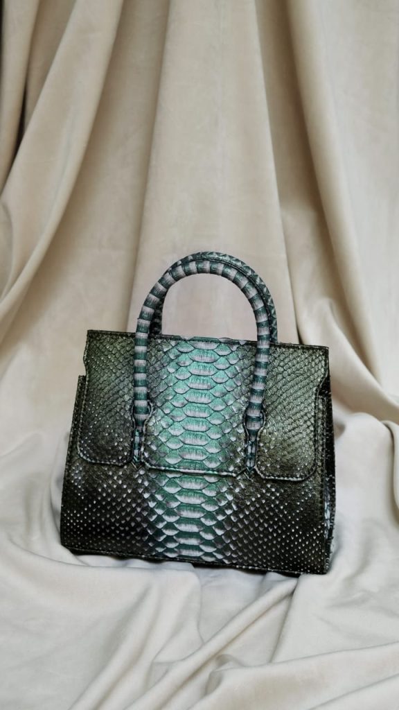 The Kyra Adriana luxury leather bag featuring a unique handle and integrated glasses holder, the perfect multifunctional leather bags UAE for travel and formal events.