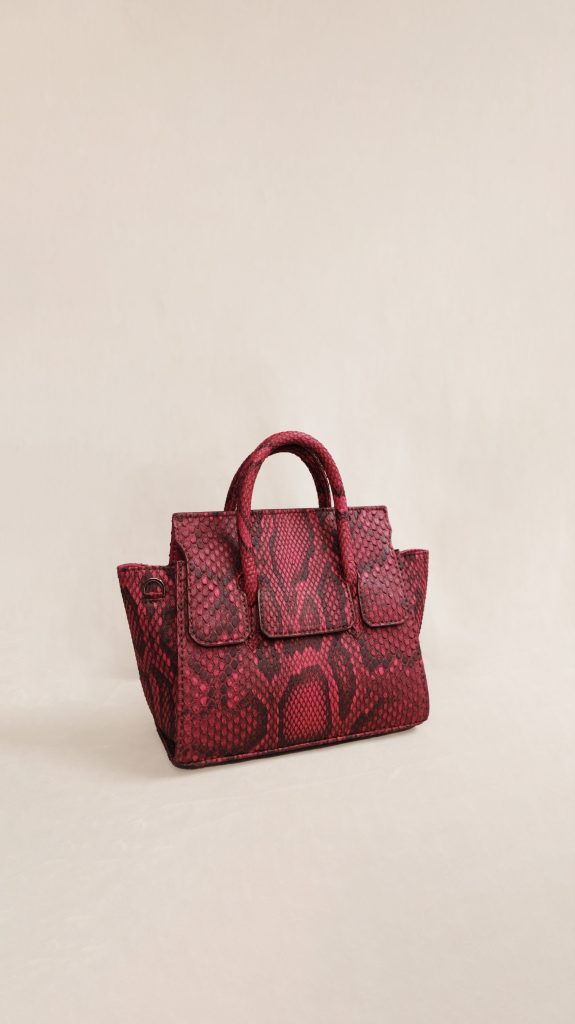 KYRA Adriana Small Dark Fuschia python leather bag featuring a bold pink semiclassical design with a unique handle, glasses holder, and expandable side wings for Eid 2026.