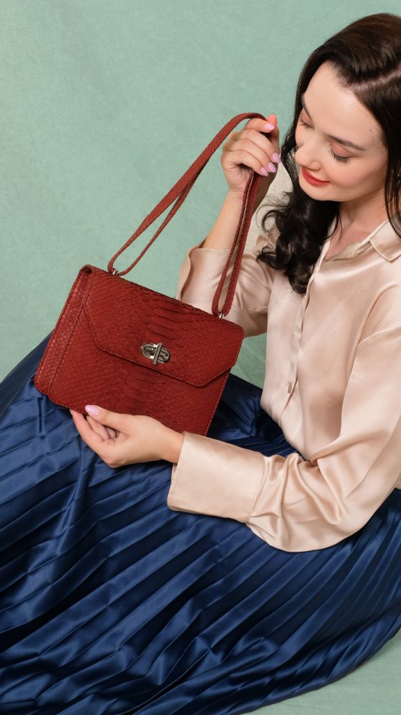 KYRA Cosette Rum Raisin exotic python leather handbag featuring an adjustable top handle, structured compact design, and suede lining for Eid 2026.