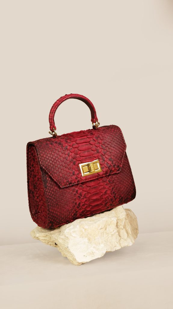 KYRA Luna Burgundy structured python leather mini bag featuring a boxy design with a gold signature lock and elegant shoulder strap for Eid 2026.