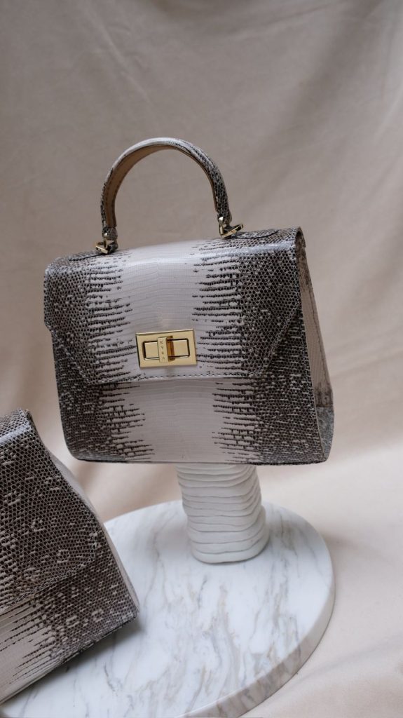The KYRA Luna boxy structured lizard leather bag with a signature gold lock, an elegant luxury business gift for Eid 2026 in Doha.