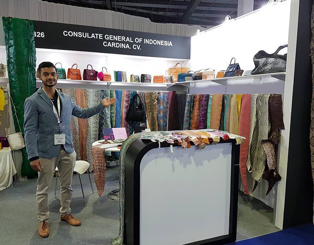 Rifky from the second generation of Cardina showcasing premium leather materials and finished bags at a luxury exhibition booth.