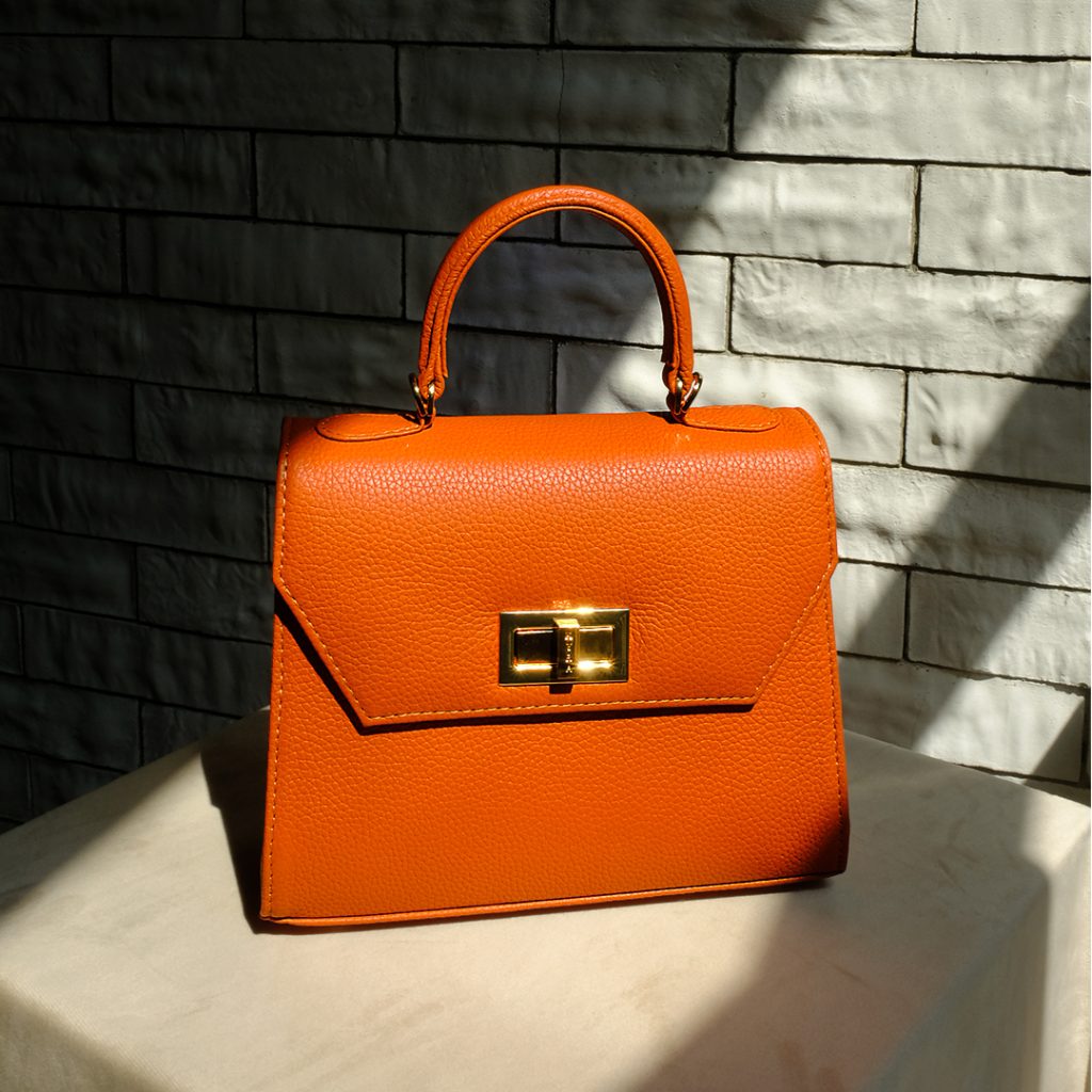 KYRA Luna Bag in vibrant orange calf leather with gold turn-lock hardware and top handle, a personalized exotic leather bag handcrafted for Eid Adha 2026
