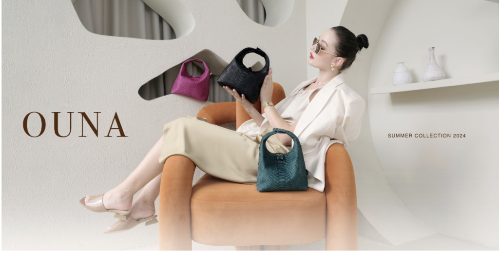 A female model sitting on an orange chair presenting the KYRA Ouna python leather bag collection in black magenta and emerald green colors for the summer campaign.